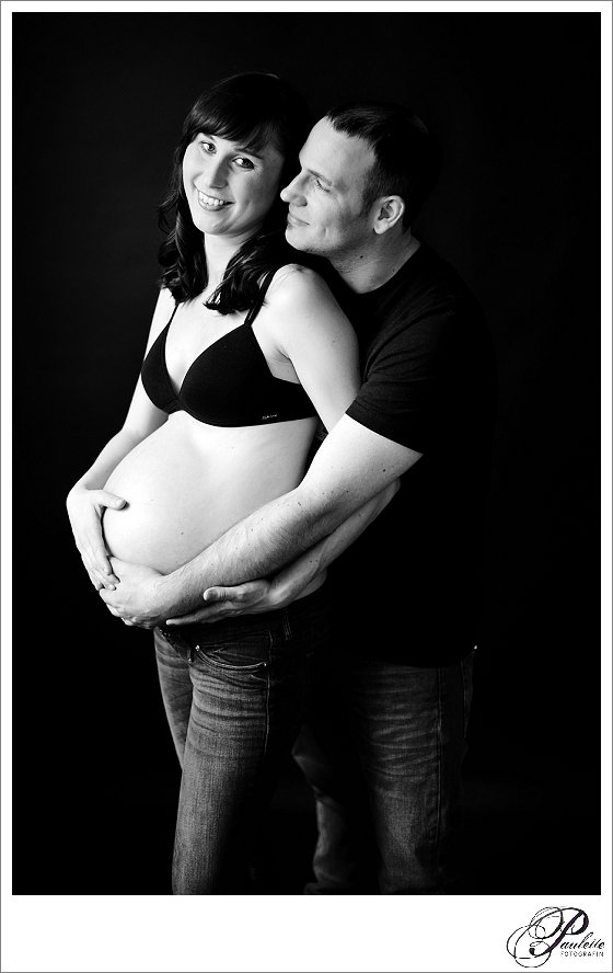 Junge werdende Eltern freuen sich auf ihr Baby beim Schwangerschaftsfotoshooting in schwarz-weiss. 